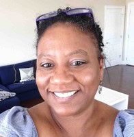 Woman with sunglasses on head smiling into camera in front of desk