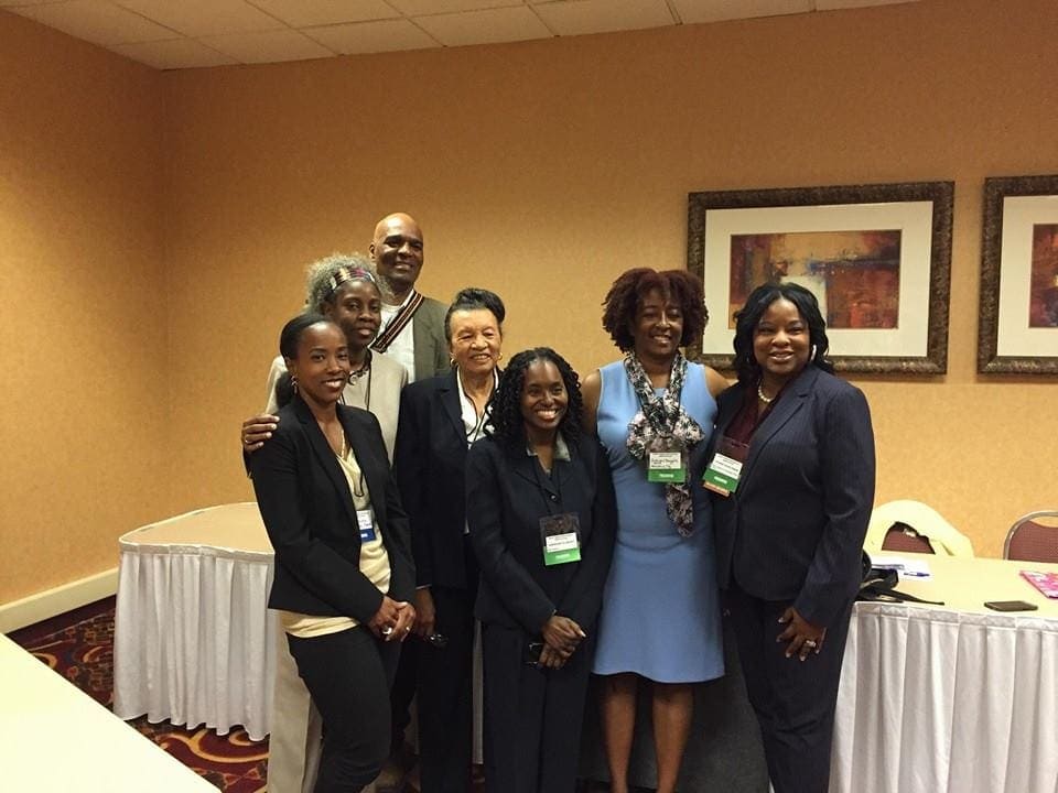 Color photograph of a group of adults inside a hotel conference room.