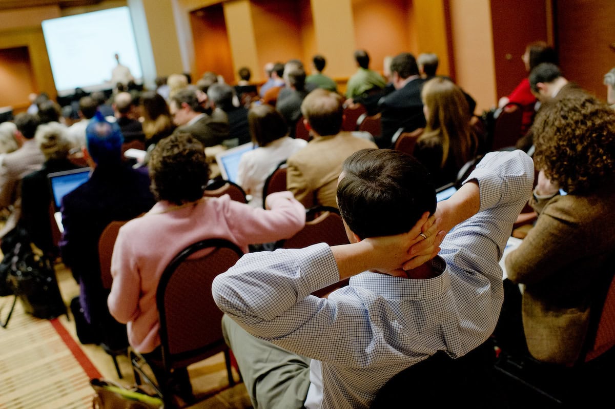 A man reclining in a chair, resting with his head tilted back and hands placed behind his head.