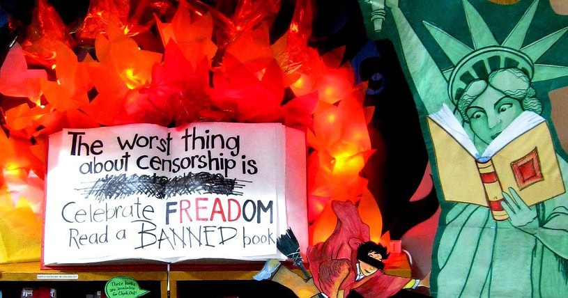 Display of a large open book that says “The worst thing about censorship is XXX Celebrate FREADOM read a banned book” with a fake fire behind it.