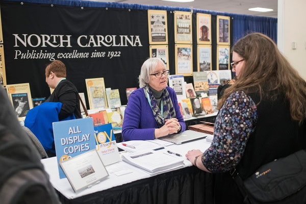 A women speaking to an attendee about conference events.