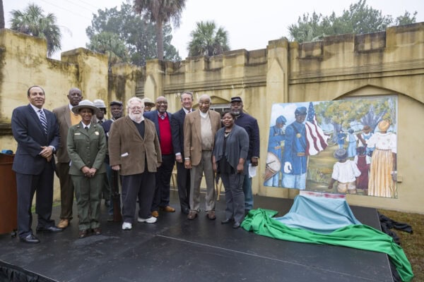 NPS staff, members of the congressional delegation, and park partners stand to the left of a Reconstruction Era National Monument. 