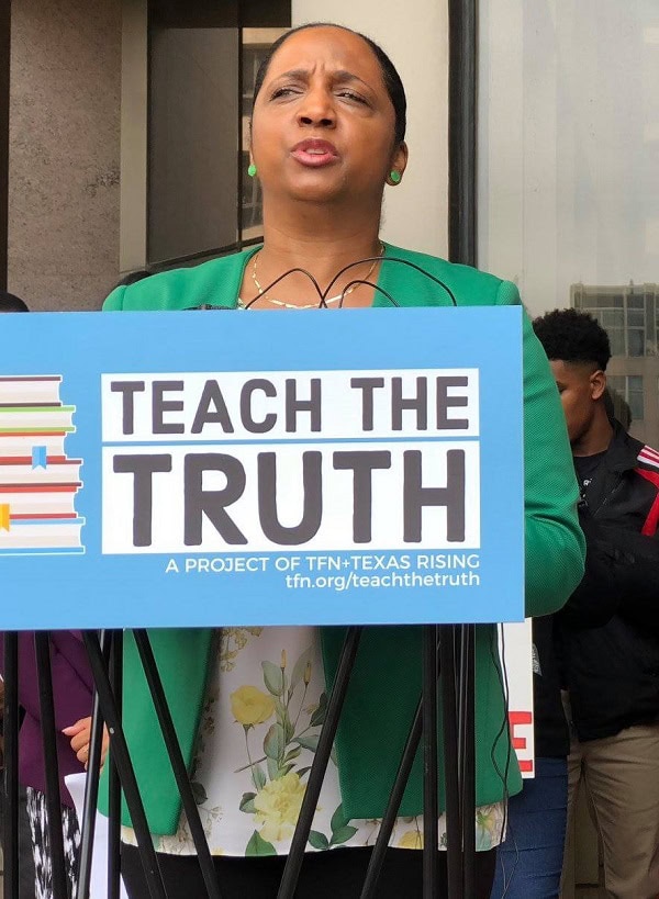 A women holding a sign that says "Teach the Truth."