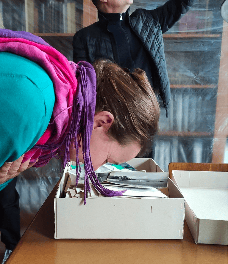 A person leaning over a box sniffing its contents.
